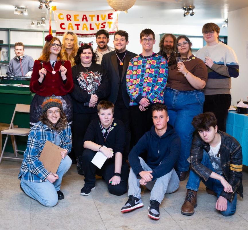 A group of young people face the camera. Behind is a banner saying "Creative Catalyst". 