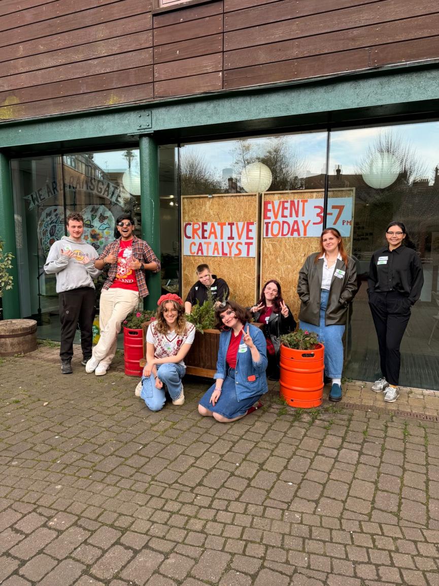 A group of young people stand outside a community space. 