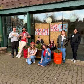 A group of young people stand outside a community space. 